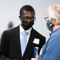 Scholar and guests wearing masks and chatting.